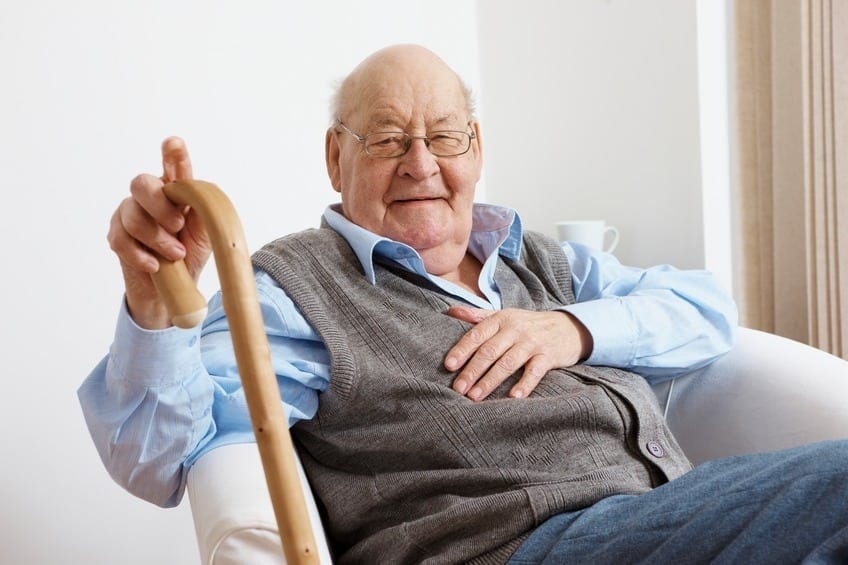 An elderly man sitting down with a walking stick