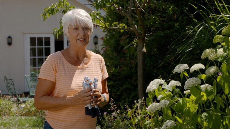 An older woman in the garden wearing a careline alarm