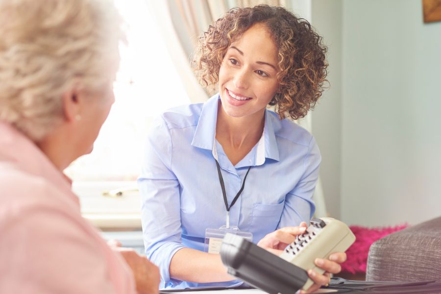 A Telecare24 staff teaching an old woman how to use key safe box