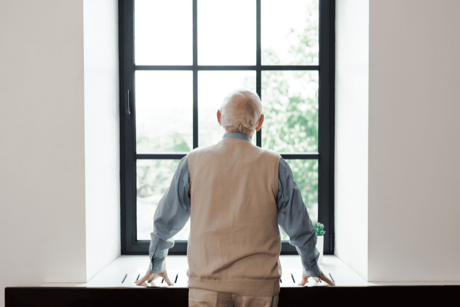 A lonely old man looking through a window